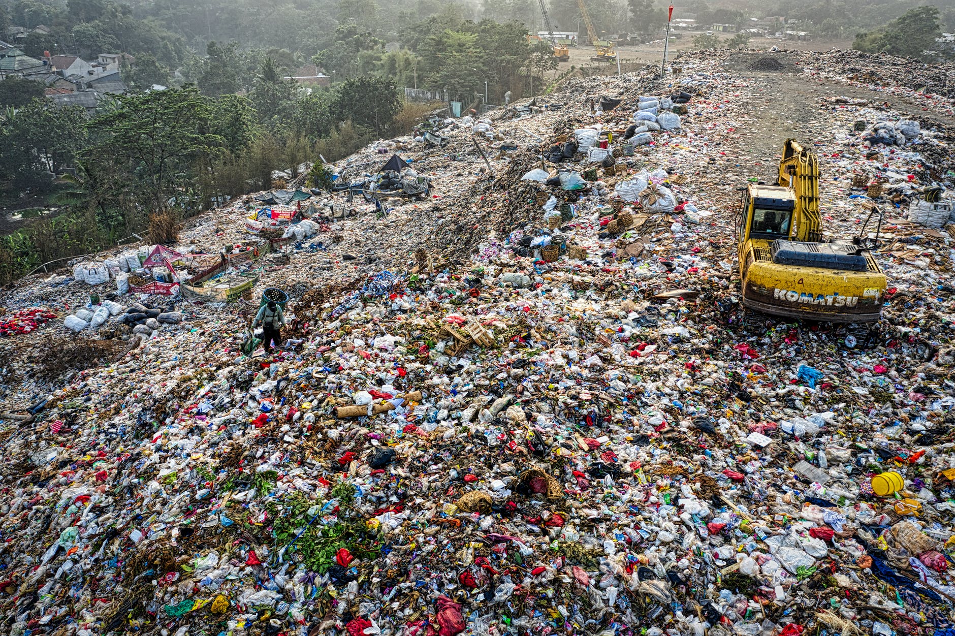 yellow excavator in garbage mountain