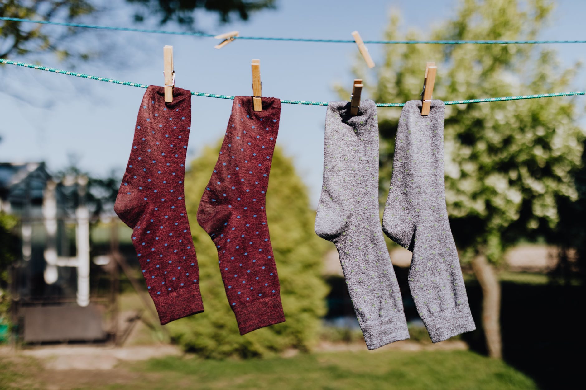 multicolored socks drying on rope with clothespins in open air