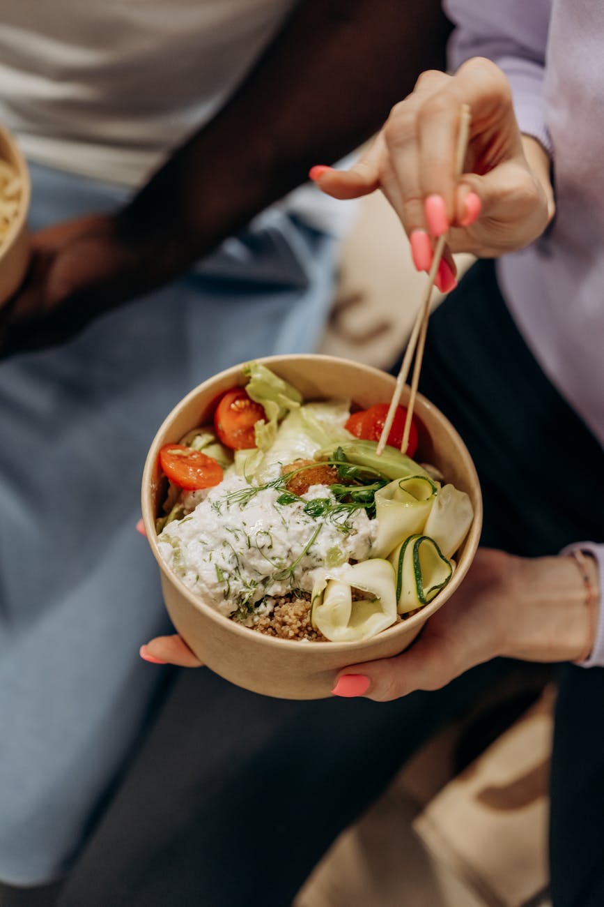 person holding a bowl with vegetable salad